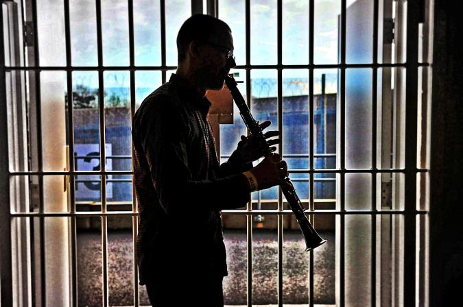 Ein Klarinettist spielt hinter vergittertem Fenster