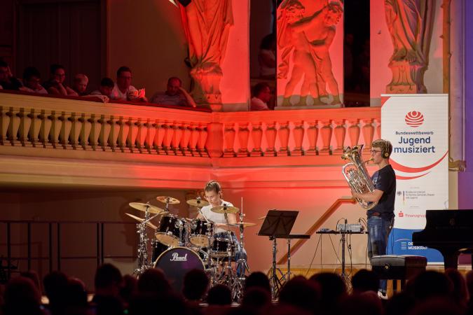 Jugendlicher Tubist und Schlagzeuger auf einer Bühne