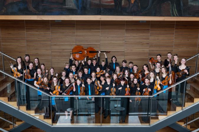 Eine Gruppe Jugendlicher mit Streichinstrumenten auf einer Treppe