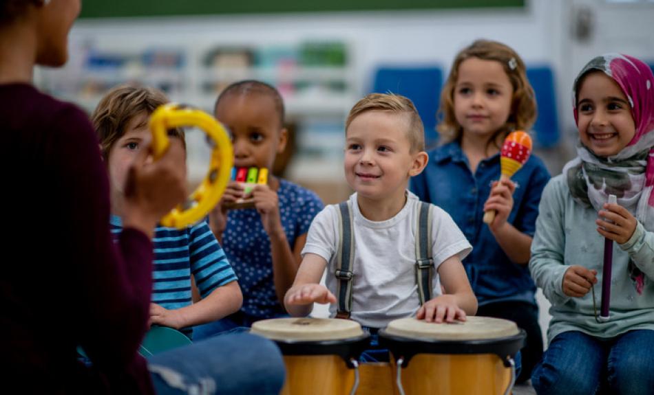 Kinder mit Rhythmusinstrumenten musizieren mit Musikpädagogin