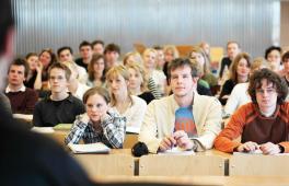 Studenten und Studentinnen in einem Hörsaal lauschen dem Professor