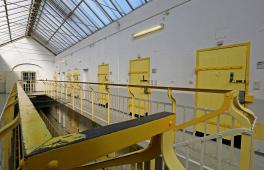 Foto eines Flurs im oberen Stockwerk eines Gefängnisses mit hellgelb gestrichenen Türen