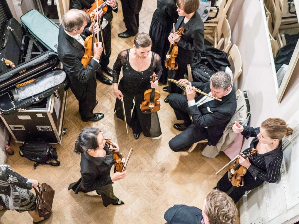 Orchestermusiker im Backstage-Bereich mit Streichinstrumenten und Querflöte