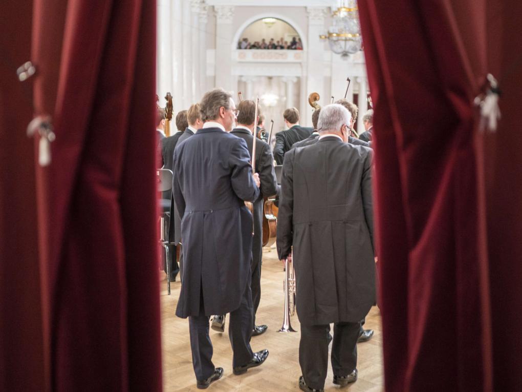 Blick durch den Vorhang auf die Orchestermusiker