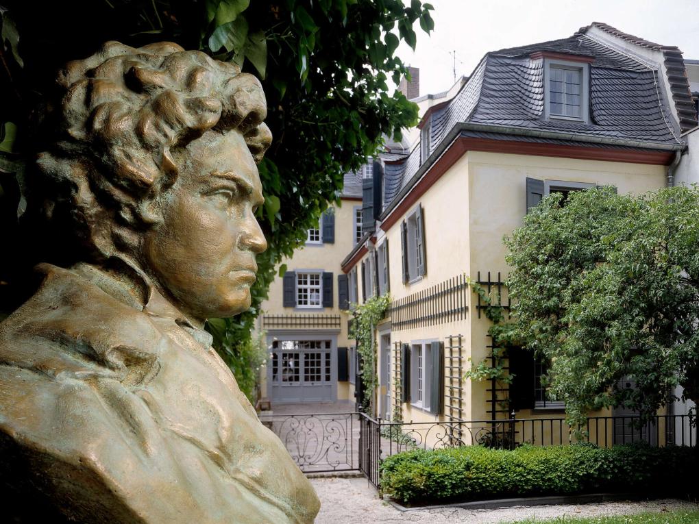 Außenansicht eines gelben Gebäudes, davor eine Beethoven-Büste