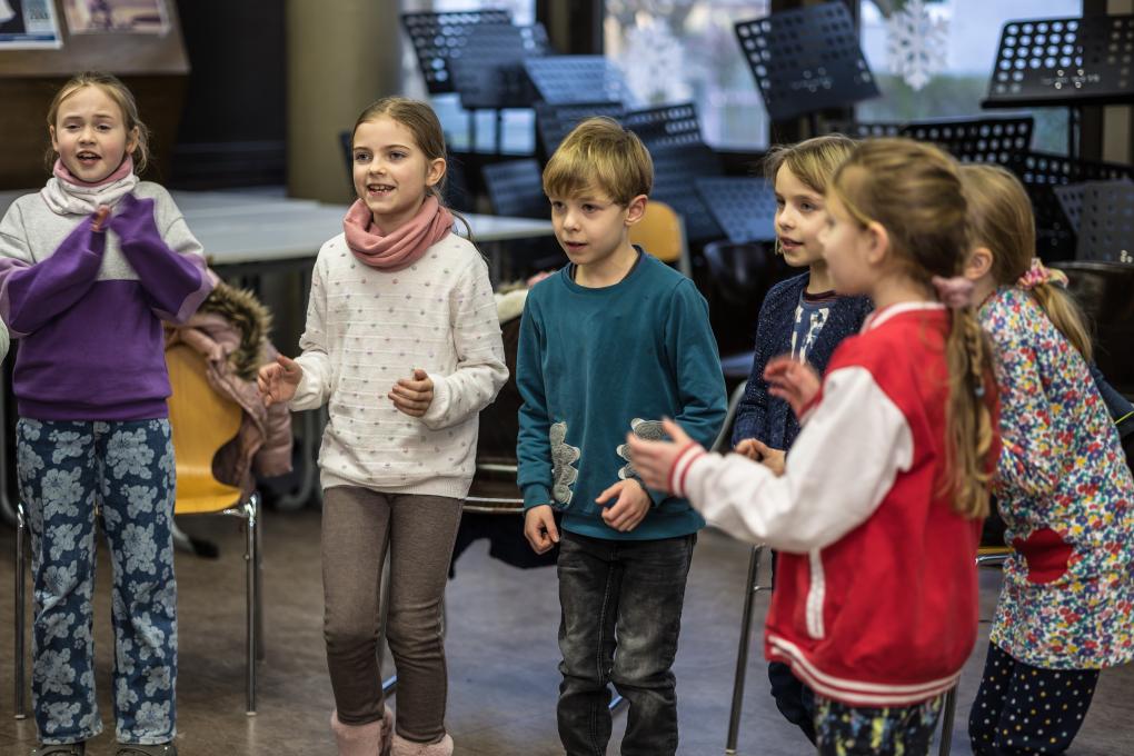 Kinder stehen klatschend und singend im Kreis