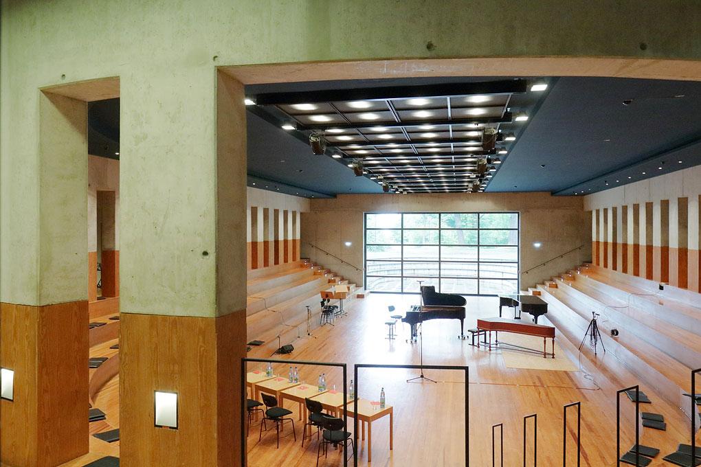 Konzertsaal mit aufsteigenden Sitzreihen, verschiedene Tasteninstrumente im Zentrum
