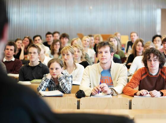 Studenten und Studentinnen in einem Hörsaal lauschen dem Professor