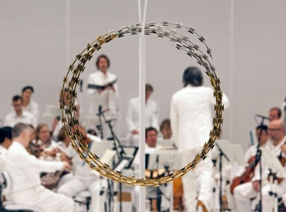 Während der Aufführung von "Las Passione" ist das Orchester ganz in weiß gekleidet. Im Vordergrund ist ein großer goldener Ring aus Draht positioniert, der an eine Dornenkrone erinnert.