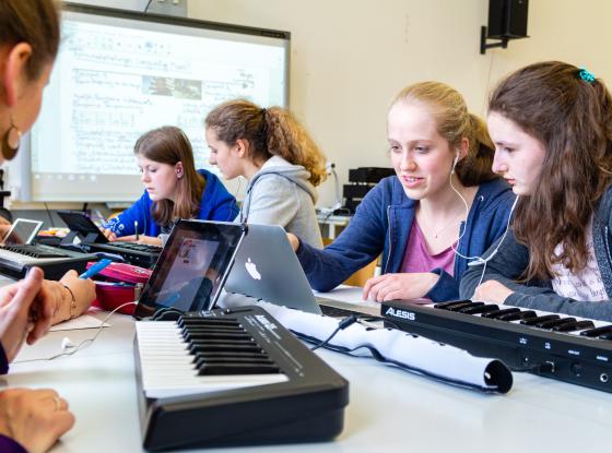 Mädchen mit Keyboards, Tablets und Kopfhörern in einem Klassenraum