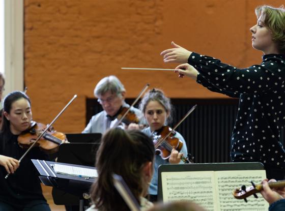 Abbildung: Dirigentin mit OrchestermusikerInnen